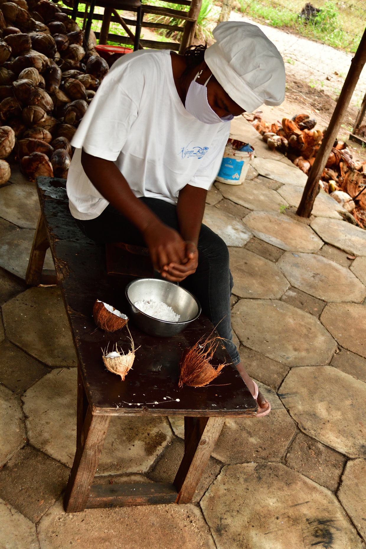 Scraping out coconut meat using the traditional method of a coconut stool.